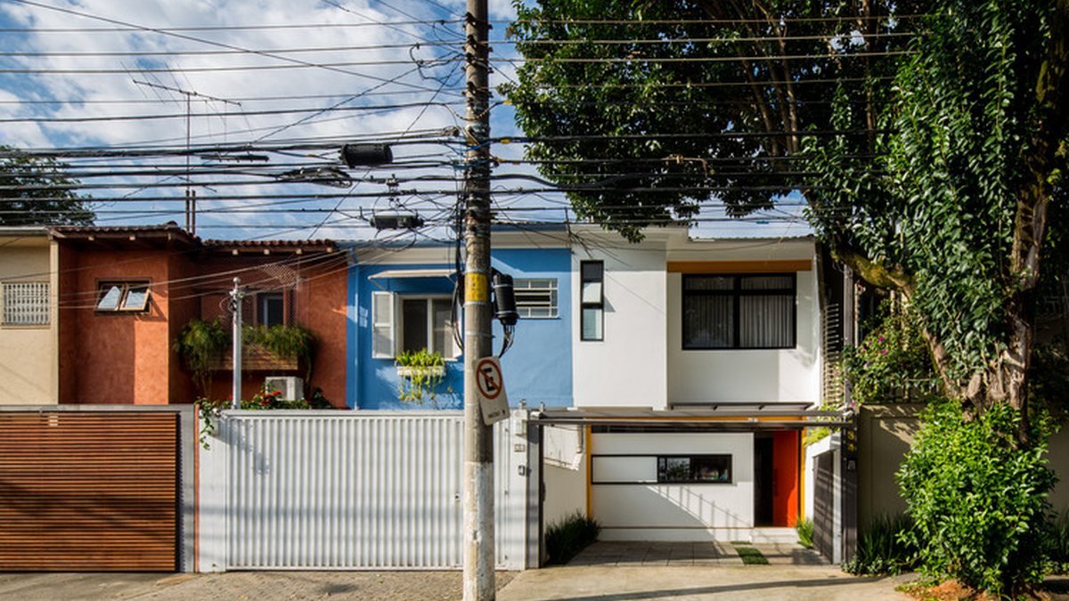 Rua de bairro com casas de fachadas coloridas em um dia de sol.